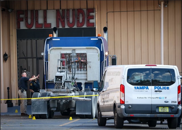 Investigators look for clues near the scene after one person was killed and two others were injured when a man drove the cab of a semi-truck into the Emperors Gentleman Club in Tampa. Police said the man had been kicked out of the club earlier.