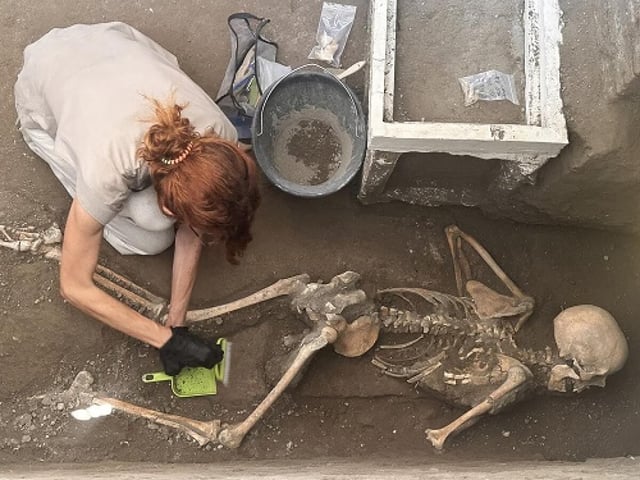 Researchers examine a new victim unearthed in the ancient city of Pompeii (credit: pompeiisites.org)