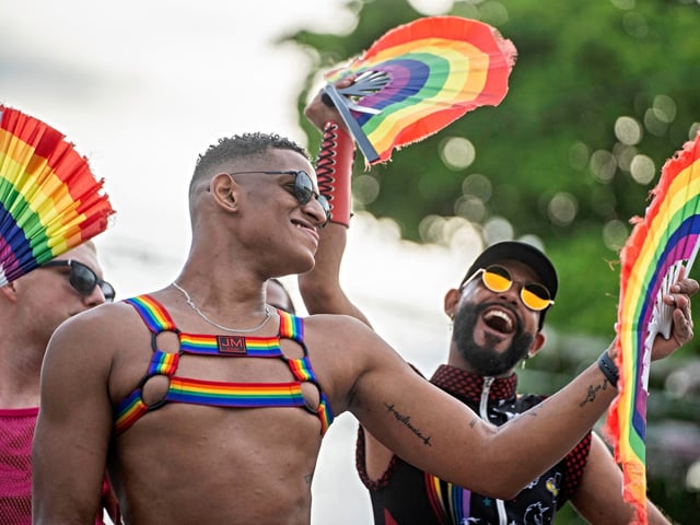 Activists of the Lesbian, Gay, Bisexual, and Transgender (LGBT+) community hold rainbow-colored hand fans during a rally in Santo Domingo on August 11, 2024. (Photo by Francesco SPOTORNO / AFP)
