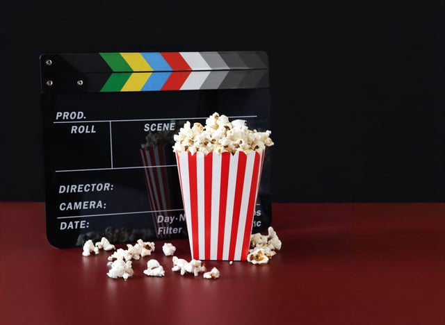 Stock photo showing close-up view of popcorn in a red and white striped cardboard carton a popular snack eaten in movie theatre cinemas.