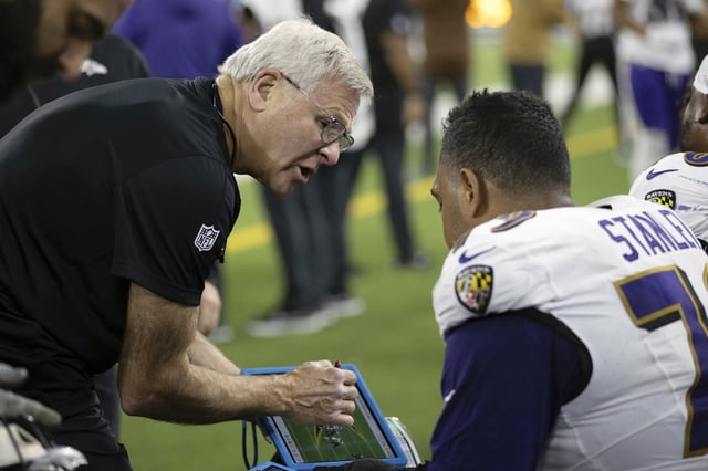 Baltimore Ravens offensive line coach Joe D'Alessandris looks at a play tablet on the sideline with offensive tackle Ronnie Stanley (79) during an NFL football game against the Los Angeles Chargers on Nov. 26, 2023. The Ravens won 20-10.
