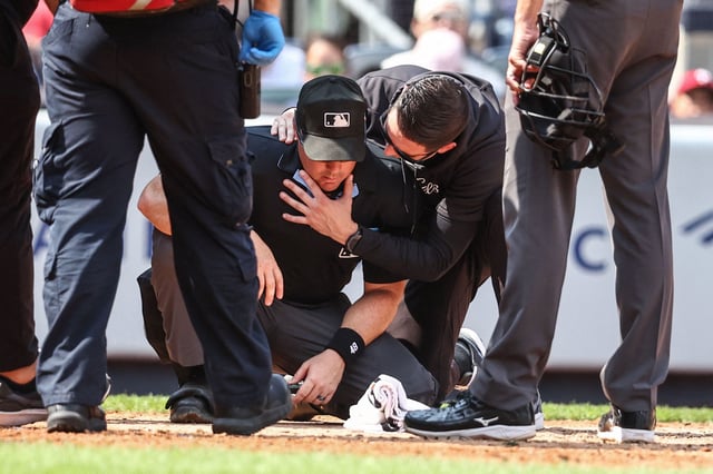 Aug 25, 2024; Bronx, New York, USA;  Home plate umpire Nick Mahrley (48) is checked on after getting hit by a broken bat in the fifth inning during the game between Colorado Rockies and New York Yankees at Yankee Stadium. Mandatory Credit: Wendell Cruz-USA TODAY Sports