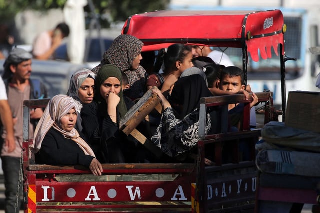 Palestinian women and children sit in the back of a vehicle as they flee Deir el-Balah in the central Gaza Strip on August 21, 2024.