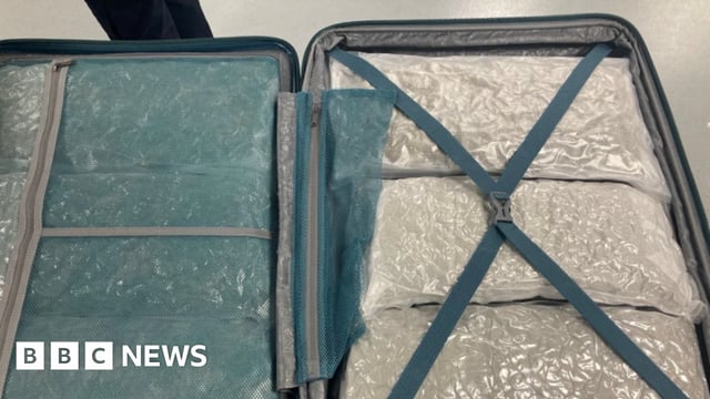 An opened suitcase stuffed with packages wrapped in plastic