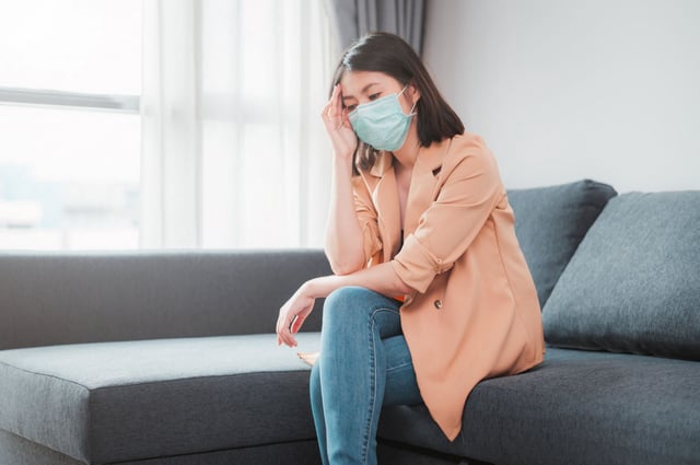 Woman wearing face mask feeling sick