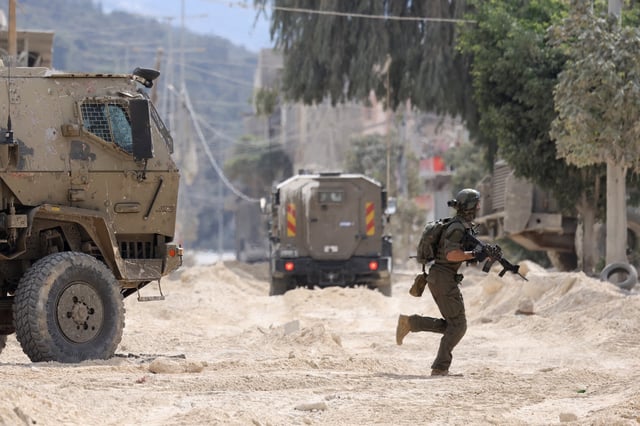 TOPSHOT - An Israeli soldier operates during a raid in the Nur Shams camp for Palestinian refugees near the city of Tulkarem in the Israeli-occupied West Bank on August 28, 2024. At least 10 Palestinians were killed in Israeli raids and strikes in several towns in the north of the occupied West Bank, a spokesman for the Red Crescent said on August 28. The operation comes two days after Israel said it carried out an air strike on the West Bank that the Palestinian Authority reported killed five people. (Photo by JAAFAR ASHTIYEH / AFP) (Photo by JAAFAR ASHTIYEH/AFP via Getty Images)