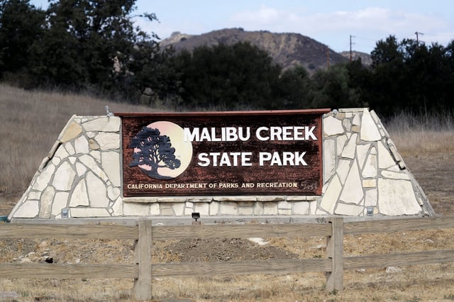 FILE - A sign stands at the entrance to the Malibu Creek State Park in Calabasas, Calif., Oct. 11, 2018. A man convicted in the shooting death of a father who was camping with his daughters at the park was sentenced on Wednesday, June 7, 2023, to 119 years to life in prison. A jury last month found Anthony Rauda guilty of second-degree murder in the death of  and of the attempted murders of the two young girls. (AP Photo/Marcio Jose Sanchez, File)