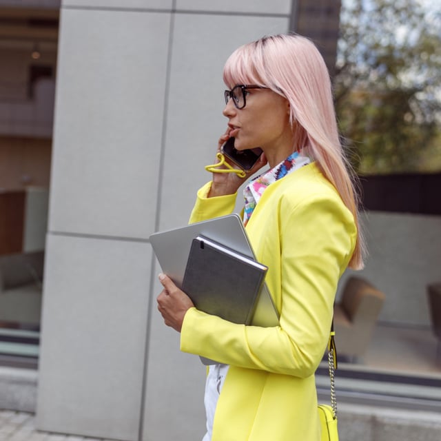 A file photo of a young woman walking, talking on the phone with laptop in hand. A survey has found the things Gen Z are most likely to save in an emergency.