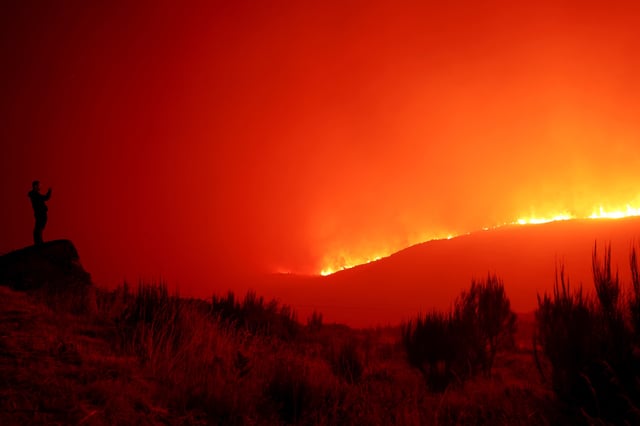 A man stands in the vicinity of wildfire, near Povoa de Montemuro, Portugal, September 18, 2024. REUTERS/Susana Vera/File Photo