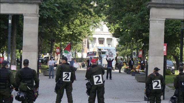 Police stand by as protesters holds up signs at McGill University in Montreal, on July 10. (AP)