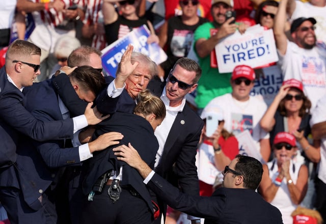 republican presidential candidate and former U.S. President Donald Trump gestures with a bloodied face while he is assisted by U.S. Secret Service personnel after he was shot in the right ear during a campaign rally at the Butler Farm Show in Butler, Pennsylvania, U.S., July 13, 2024. REUTERS/Brendan McDermid/File Photo